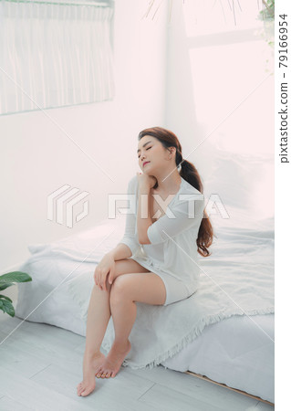 Adult attractive dreamy lady touching neck sitting bed Adult attractive dreamy lady touching neck sitting bed 79166954
