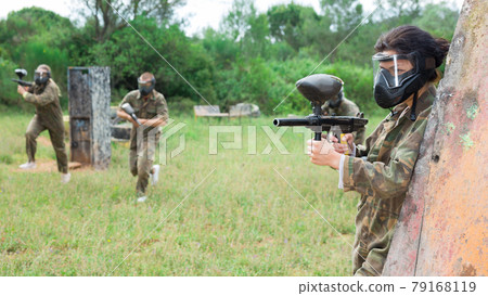 Group of friends paintball players of opposite teams in shootout in forest Group of friends paintball players of opposite teams in shootout in forest 79168119