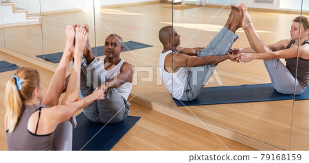 Yoga teacher helps couples learn yoga poses Yoga teacher helps couples learn yoga poses 79168159