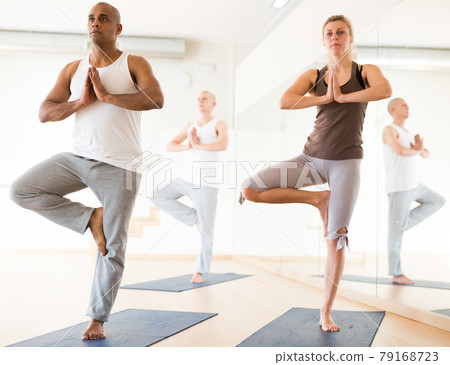 Woman and man standing in balancing pose Eka Pada Pranamasana Woman and man standing in balancing pose Eka Pada Pranamasana 79168723