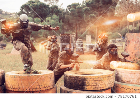 Two active opposing teams with guns playing paintball 79170761