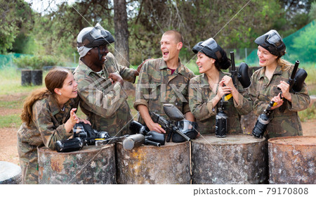 Smiling friends chatting after successful paintball match Smiling friends chatting after successful paintball match 79170808