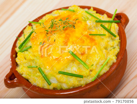 Scottish cuisine. Mix of mashed potatoes, fried cabbage, onions and cheddar cheese served in clayware with greens. Scottish cuisine. Mix of mashed potatoes, fried cabbage, onions and cheddar cheese served in clayware with greens. 79170856