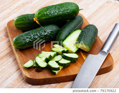 Cucumbers and knife on wooden cutting board 79170922