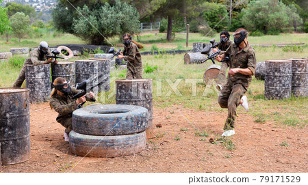 Two active opposing teams with guns playing paintball Two active opposing teams with guns playing paintball 79171529