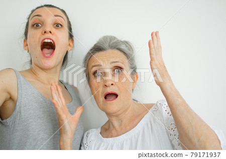 Emotional adult daughter with her senior moter are screaming and looking at the camera, crazy family of different age generations having fun on white background, mothers day Emotional adult daughter with her senior moter are screaming and looking at the camera, crazy family of different age generations having fun on white background, mothers day 79171937