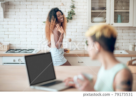 Turning smiling dark-skinned woman and girlfriend at laptop Turning smiling dark-skinned woman and girlfriend at laptop 79173531