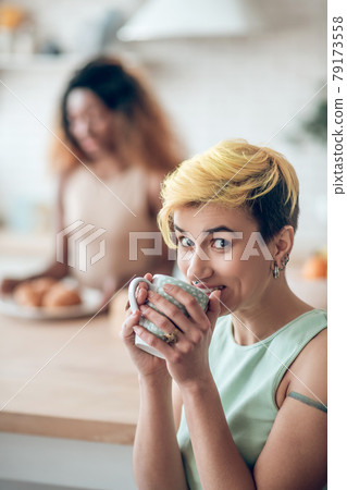 Cheerful woman drinking coffee and friend at distance Cheerful woman drinking coffee and friend at distance 79173558