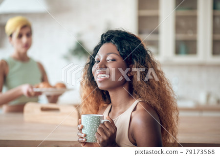 Happy smiling african american woman with coffee and girlfriend Happy smiling african american woman with coffee and girlfriend 79173568