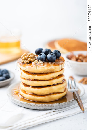 Stack of pancakes served with syrup, blueberries and walnuts 79174191