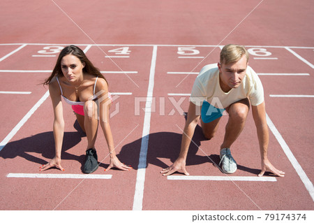 Equal forces concept. Man and woman low start position Equal forces concept. Man and woman low start position 79174374