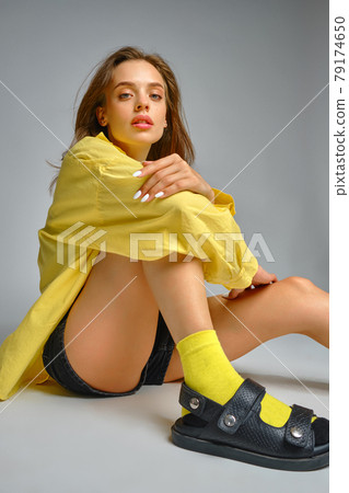 Stylish young girl sitting on grey studio background Stylish young girl sitting on grey studio background 79174650