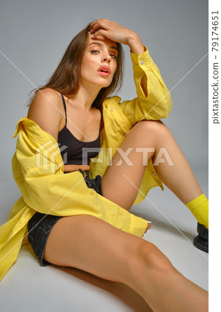 Young seductive fashion model posing sitting on grey background 79174651