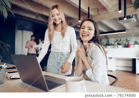 Two young happy businesswomen celebrating project success in office Two young happy businesswomen celebrating project success in office 79174880