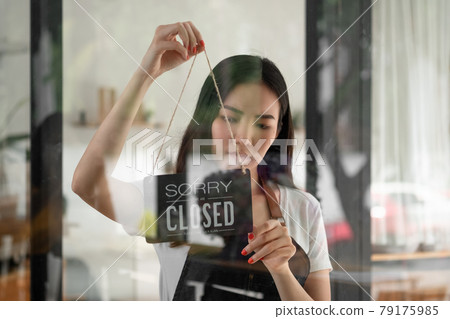 woman entrepreneur hand turning close sign board on glass door in coffee shop or restaurant during coronavirus lockdown quarantine.Owner small business, food and drink, business reopen again concept 79175985