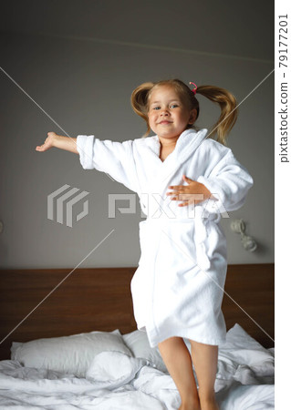 little cute girl in a white robe jumping on the bed little cute girl in a white robe jumping on the bed 79177201