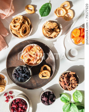 Flat lay composition of various dried fruits and berries in bowls on white background with shadows. Vegan healthy natural snacks. 79177820