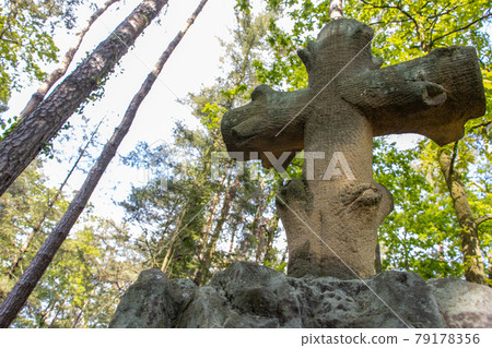 A stone Christian cross under the treetops. A stone Christian cross under the treetops. 79178356