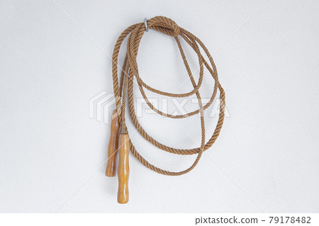 A old skipping rope hanging on a white wall. A old skipping rope hanging on a white wall. 79178482