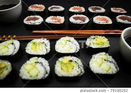 Delicious Japanese sushi next to wooden chopsticks on a black board. Delicious Japanese food Delicious Japanese sushi next to wooden chopsticks on a black board. Delicious Japanese food 79180282