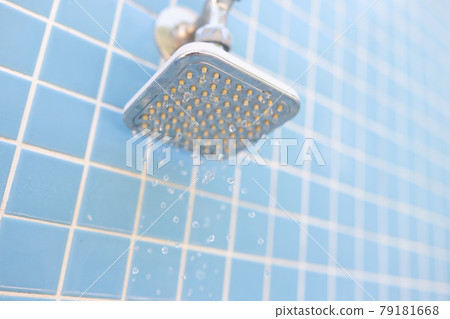 Wall mounted chrome shower on blue tiles with water drops 79181668