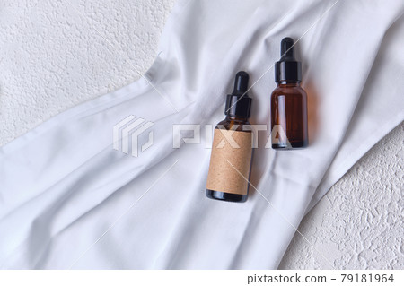 essential oil brown bottles on white fabric on white textured background 79181964