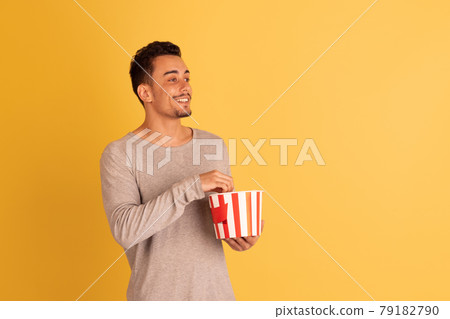 Crazy shocked, flying popcorn. Caucasian young man's portrait isolated on blue studio background. Beautiful male model in casual style. Crazy shocked, flying popcorn. Caucasian young man's portrait isolated on blue studio background. Beautiful male model in casual style. 79182790