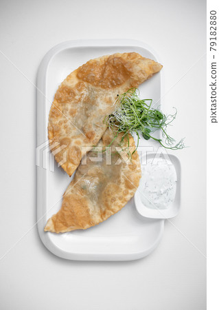 cheburek or fried dough pie with meat feeling and sauce on white background 79182880
