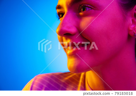 Caucasian young woman's portrait on dark studio background in neon. Concept of human emotions, facial expression. Caucasian young woman's portrait on dark studio background in neon. Concept of human emotions, facial expression. 79183018