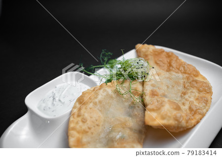 cheburek or fried dough pie with meat feeling and sauce on black background 79183414