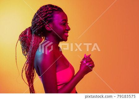 Joyful young beautiful African girl, female fashion model isolated on yellow background in neon. Concept of human emotion, facial expression. 79183575