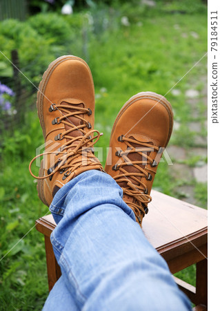 Brown boots and jeans on the legs. Legs are crossed on the stool. Brown boots and jeans on the legs. Legs are crossed on the stool. 79184511
