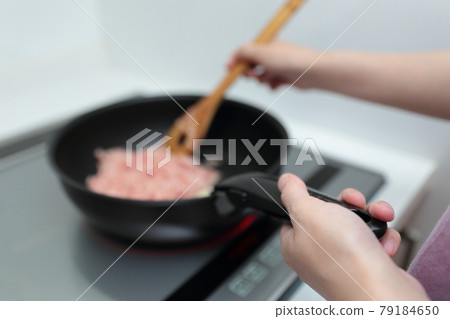 Housewife woman cooking with a frying pan on an IH cooking heater Housewife woman cooking with a frying pan on an IH cooking heater 79184650