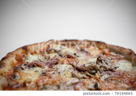 closeup of italian pizza with ham, mushrooms and cheese on white background closeup of italian pizza with ham, mushrooms and cheese on white background 79184665