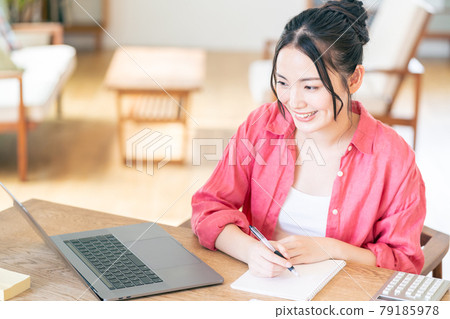 A young woman teleworking in the living room. 79185978