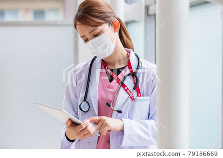 一位年輕的女醫生單手思考平板電腦數據 一位年輕的女醫生單手思考平板電腦數據 79186669