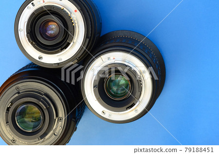 Several photographic lenses lie on a bright blue background. Space for text 79188451