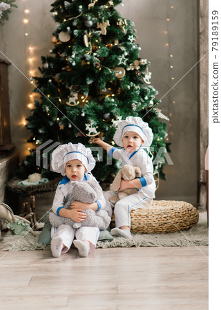 Happy funny two brothers bake christmas cookies near tree. Happy funny two brothers bake christmas cookies near tree. 79189159