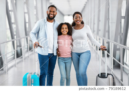Happy black family traveling, holding documents in airport Happy black family traveling, holding documents in airport 79189612