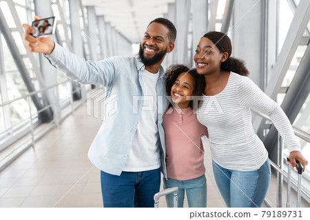Black family traveling, taking selfie on cellphone in airport Black family traveling, taking selfie on cellphone in airport 79189731