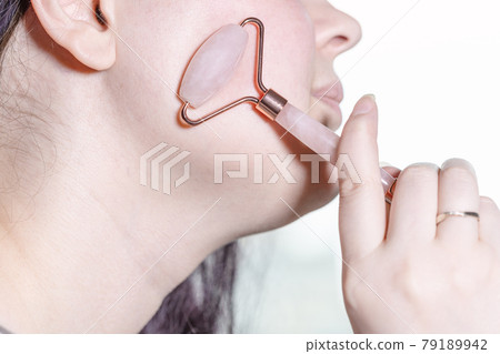 massaging cheek with quartz roller massager 79189942