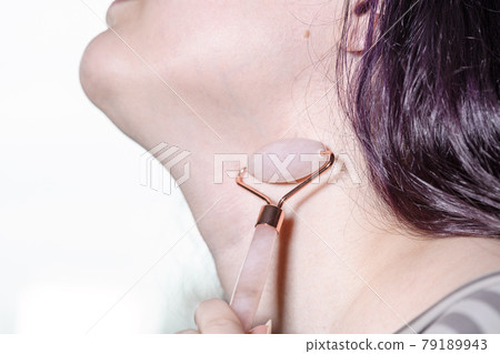 massaging female neck with quartz roller massager 79189943