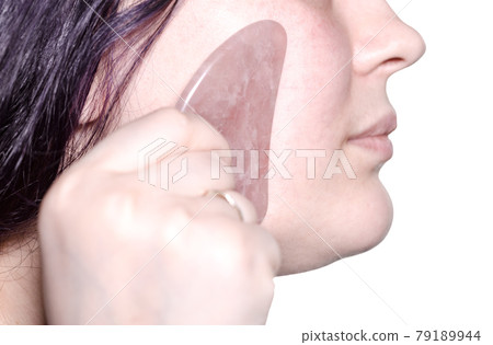 massaging female face with quartz scraper isolated 79189944