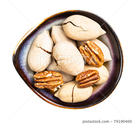 cracked and shelled pecan nuts in bowl isolated 79190400