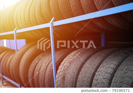 Rack with variety of car tires in automobile store. Many black tires. Tire stack background. Selective focus Rack with variety of car tires in automobile store. Many black tires. Tire stack background. Selective focus 79190571