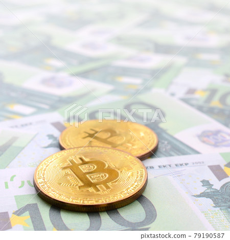 Golden physical bitcoins is lies on a set of green monetary denominations of 100 euros. A lot of money forms an infinite heap Golden physical bitcoins is lies on a set of green monetary denominations of 100 euros. A lot of money forms an infinite heap 79190587