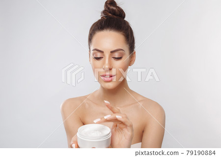 Beauty Woman Face Skin Care. Portrait Of Attractive Young Female Applying Cream And Holding Bottle. Closeup Of Smiling Girl With Natural Makeup And Fresh Skin. Cosmetics. 79190884