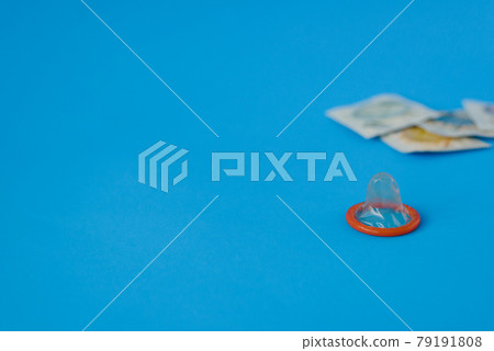 opened green condom with condom pack on blue paper background with copy space for text. Reproductive health, contraception and safe sex concept opened green condom with condom pack on blue paper background with copy space for text. Reproductive health, contraception and safe sex concept 79191808