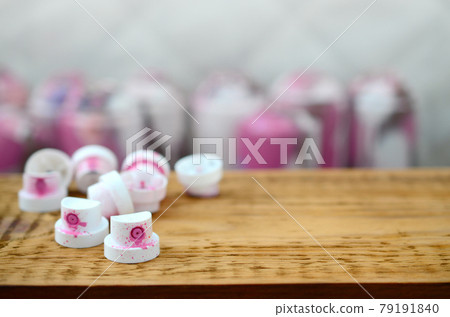 The soiled pink nozzles from the paint sprayer lies on a wooden plank on a background of a many dirty spray cans The soiled pink nozzles from the paint sprayer lies on a wooden plank on a background of a many dirty spray cans 79191840