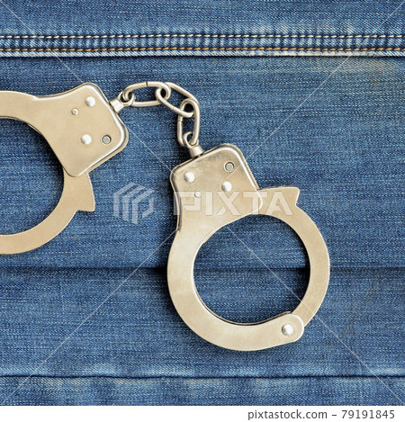 Police steel handcuffs lying on dark blue jeans background Police steel handcuffs lying on dark blue jeans background 79191845